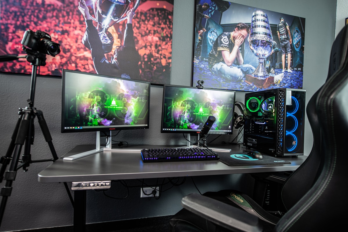 Professional streaming setup with dual monitors, camera on tripod, and esports posters on the wall